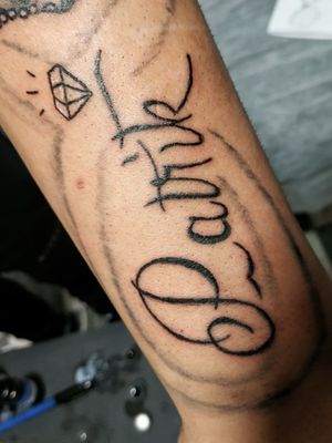 Name tattoo with little diamond above 