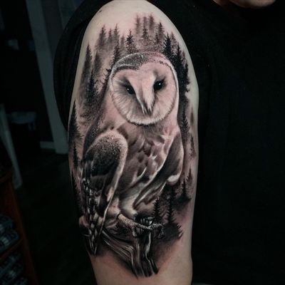 Get mesmerized by Marcel Oliveira's intricate black and gray owl and tree tattoo on your upper arm. A true work of art!