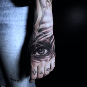 Black and gray illustrative design by Marcel Oliveira captures the detail of an eye on the hand.