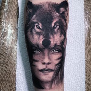 Get a stunning blackwork and realistic tattoo of a wolf and woman on your forearm by tattoo artist Marcel Oliveira.