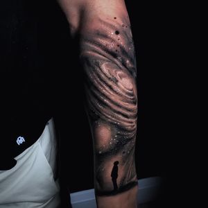 Stunning black and gray tattoo featuring a detailed galaxy, planet, and man in a realistic illustrative style by Marcel Oliveira.