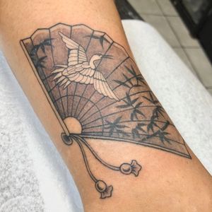 Elegantly detailed black and gray tattoo featuring a majestic crane and traditional fan by artist Sophie Rose Hunter.