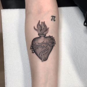 Sophie Rose Hunter creates a stunning black and gray design featuring a heart and cross on the forearm.