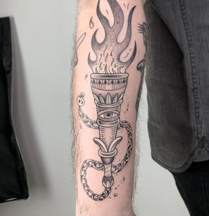 Unique black and gray design on upper arm featuring a torch, flame, eye, and chain by Galen Bryce (Drip Skull).