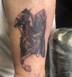 Cloaked man riding horse