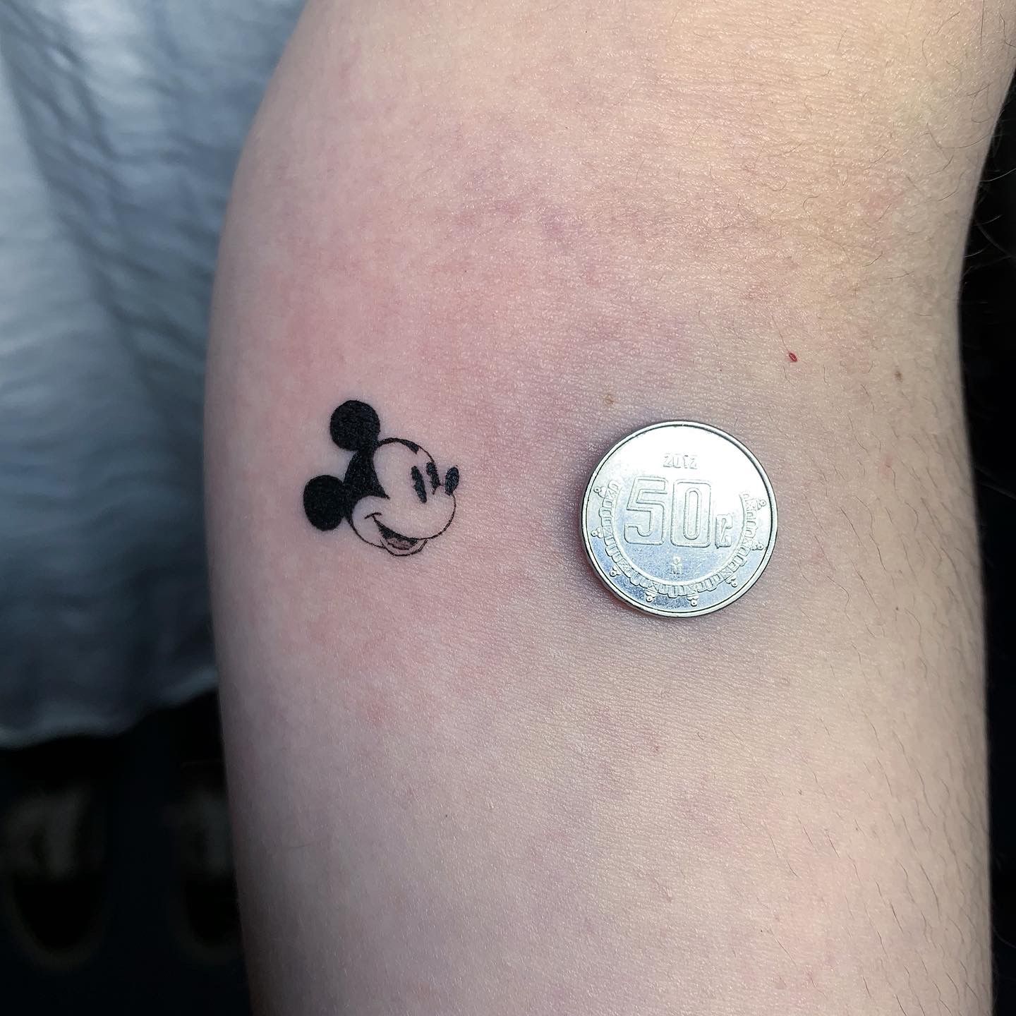 Gold Mickey Mouse tattoo located on the inner forearm.