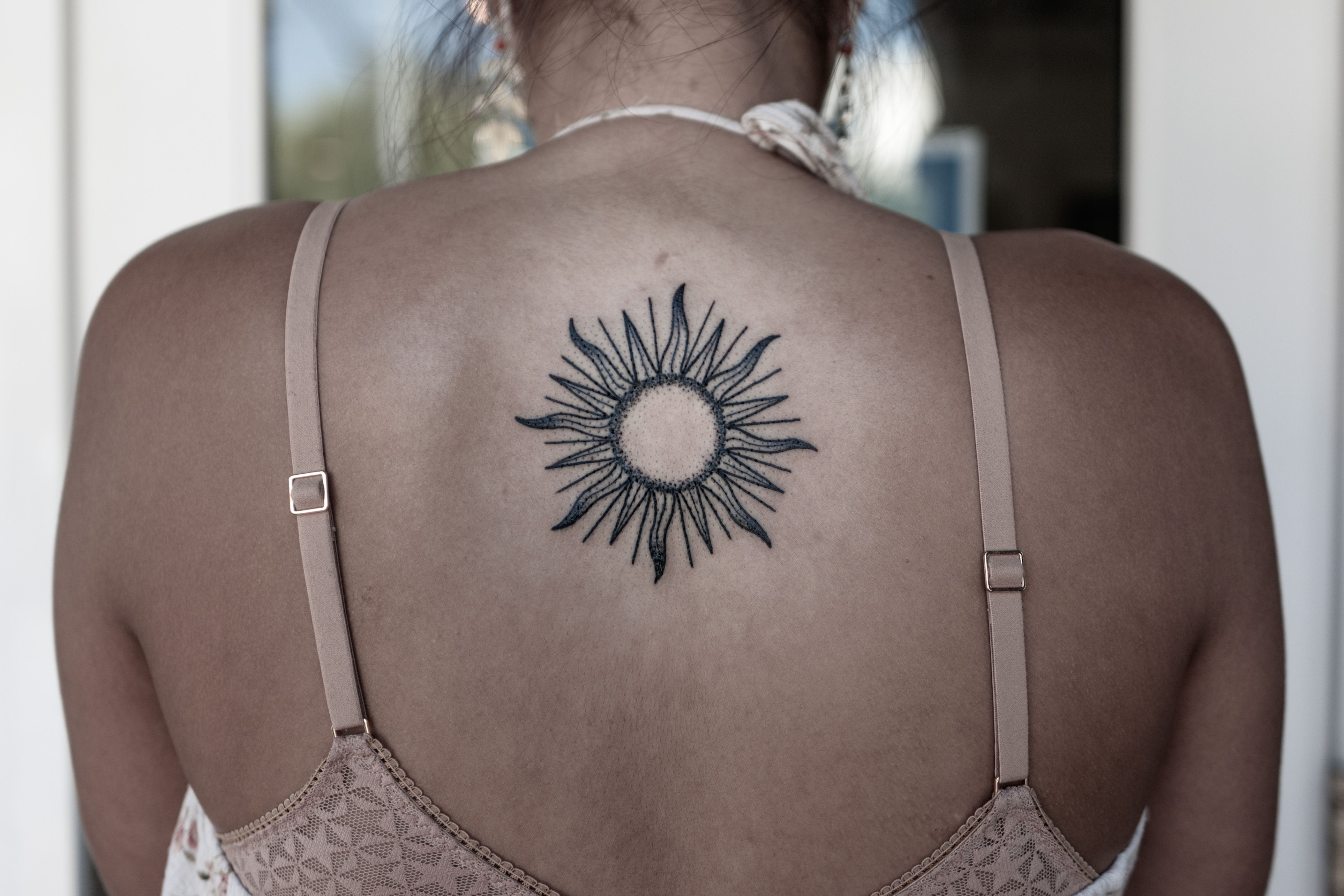 Fine line sun and moon tattoo on the upper back.