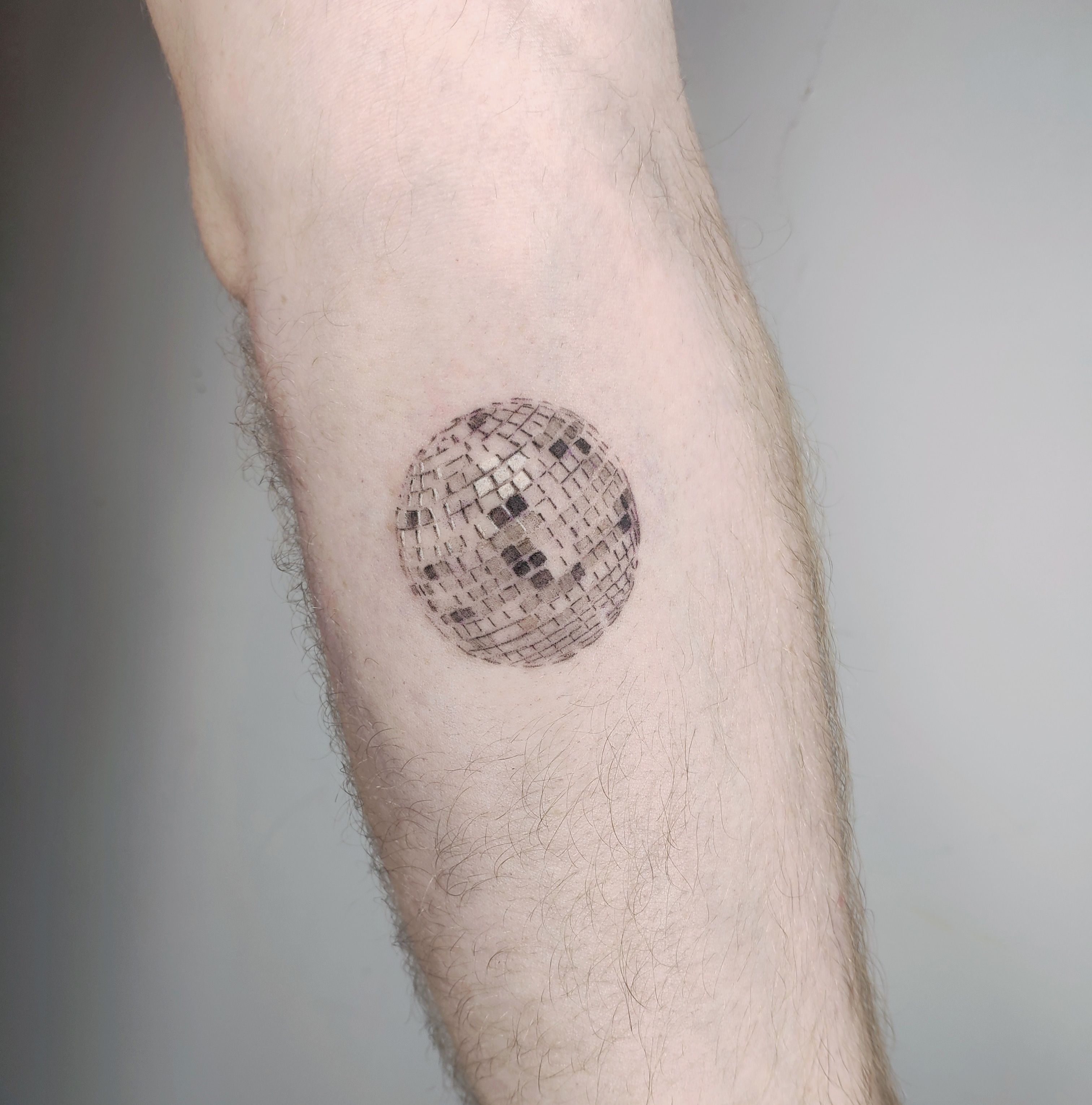 Rib tattoo of a broken disco ball micro realistic