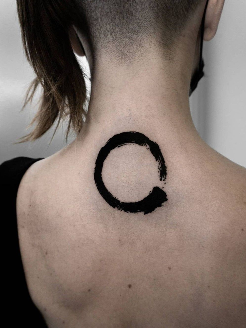 Abstract circle tattoo on the left shoulder.