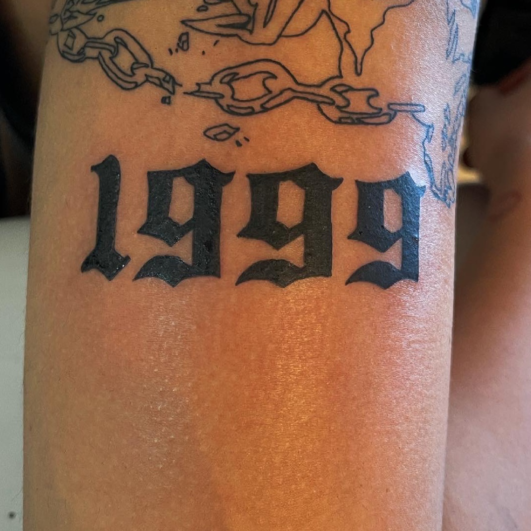 1999 lettering tattoo located on the bicep