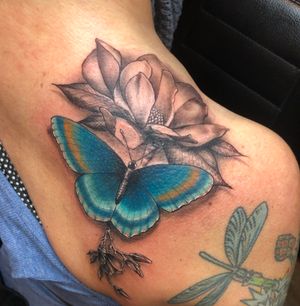 Color butterfly on a black and grey magnolia flower placed on clients shoulder.
