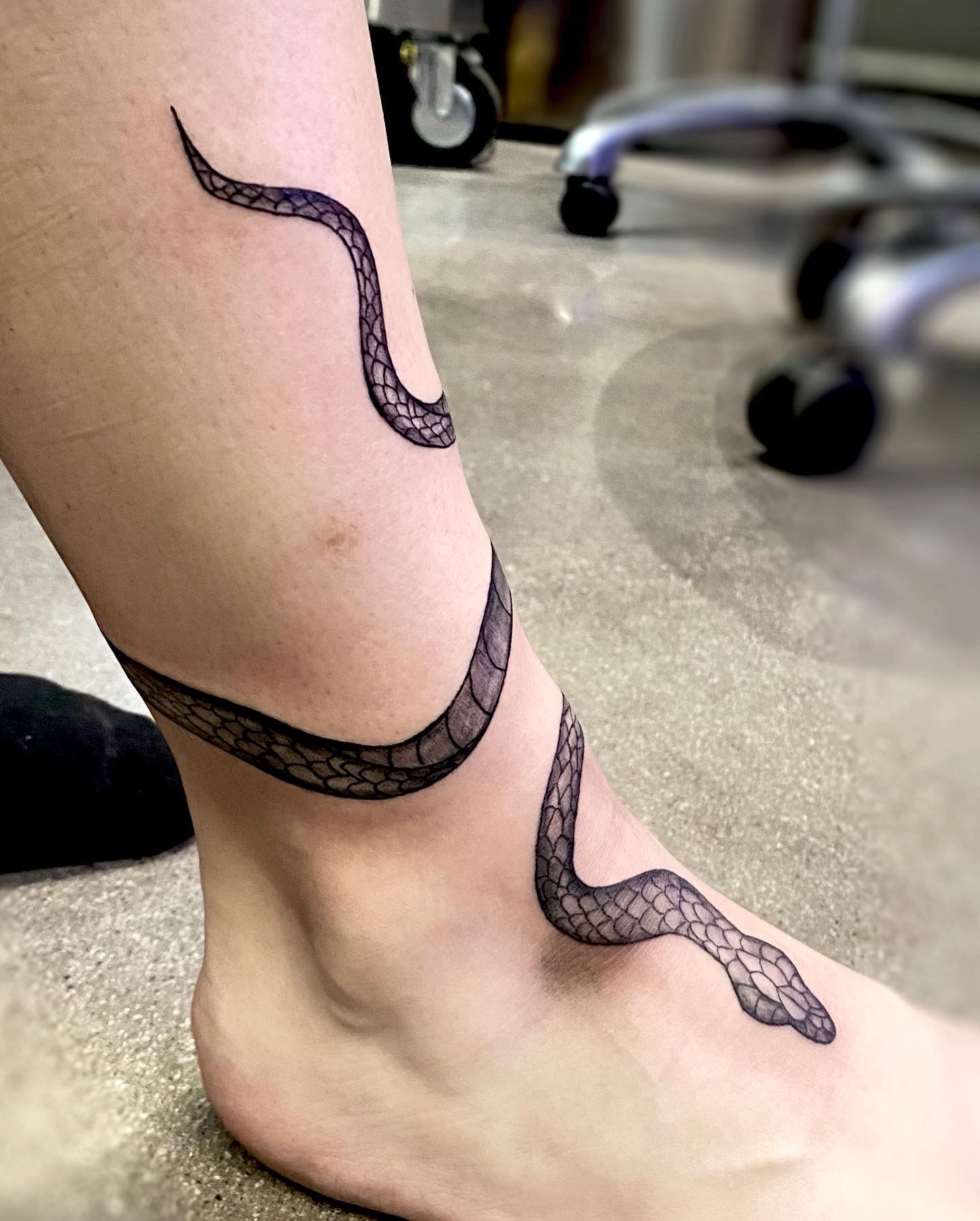 Fine line snake tattoo located on the ankle