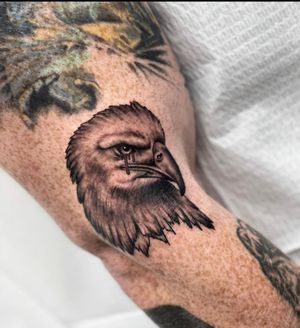 Captivating blackwork tattoo of a fierce eagle with blood accents, designed by Miss Vampira for the upper arm.
