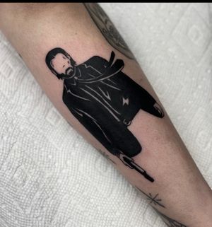 Get inked with a blackwork pistol and a portrait of Keanu Reeves as John Wick by the talented artist Miss Vampira.