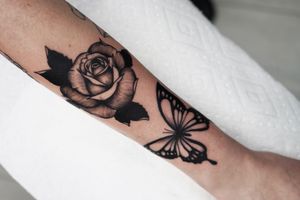 Illustrative tattoo by Miss Vampira featuring a stunning butterfly and flower motif on the forearm.