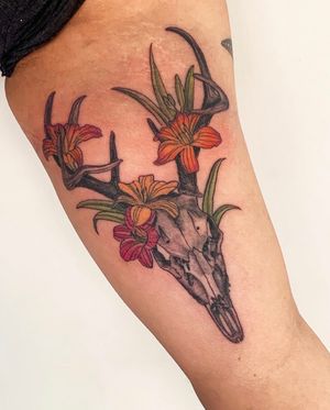 Brigid Burke creates a stunning neo-traditional tattoo of a flower intertwined with a skull on the upper arm.