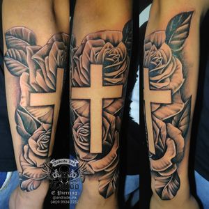 Tatuagem rosas e cruz no antebraço masculino