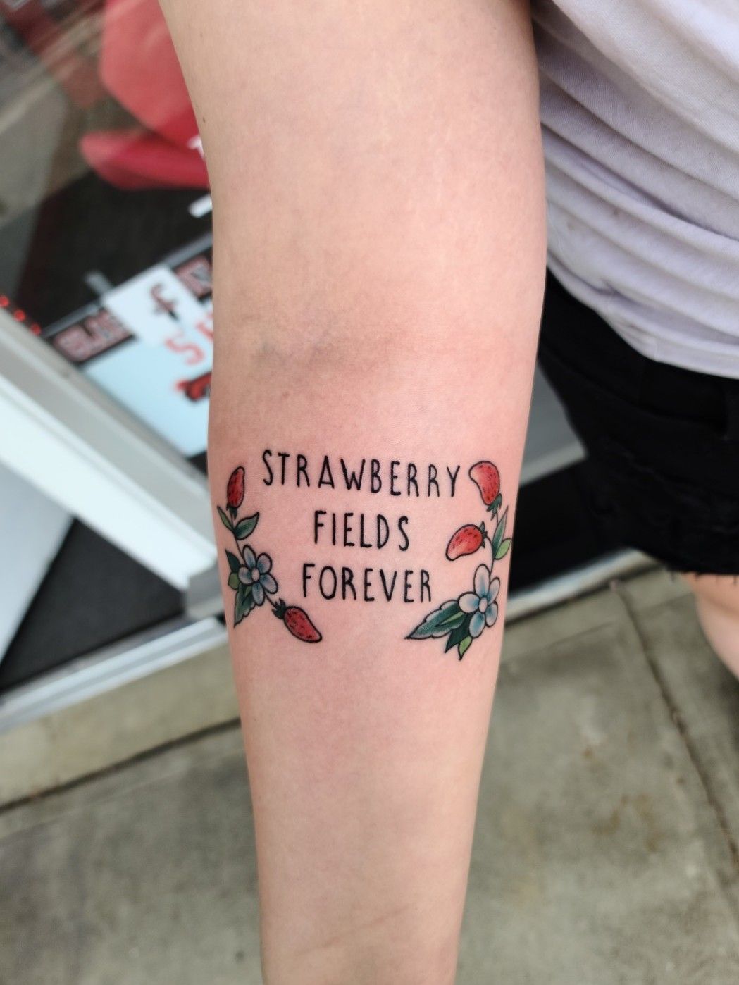 Strawberry Fields lettering tattoo in red ink