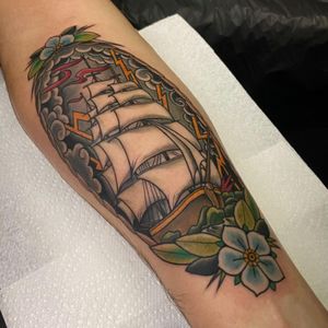 Beautiful forearm tattoo by Jethro Wood featuring a sea, ocean, flower, and ship motif in a stunning neo-traditional style.