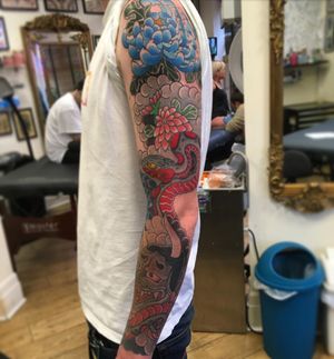 A stunning illustrative sleeve tattoo featuring a snake, chrysanthemum, and hannya mask design by talented artist Kiko Lopes.
