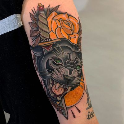 Vibrant neo-traditional forearm tattoo by Jethro Wood featuring a fierce panther, delicate flower, sinister dagger, and splashes of blood.