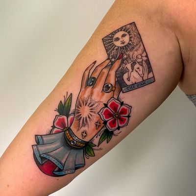 Capture the mystical energy with this neo traditional upper arm tattoo featuring a sun, horse, flower, hand, card, gipsy, ring, and tarot motifs. By artist Jethro Wood.