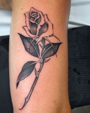 Elegant black and gray flower tattoo adorning the arm, expertly designed by Felipe Reinoso. Perfect blend of realism and artistry.