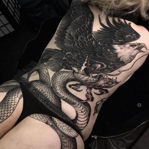 Capture the power of the snake and eagle in this stunning black and gray back tattoo in London, GB.