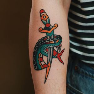 Get a stunning traditional tattoo featuring a snake and dagger motif on your arm in London, GB.