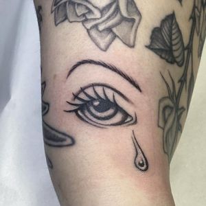 Get a unique black and gray new school tattoo of an eye shedding tears on your upper arm in London!