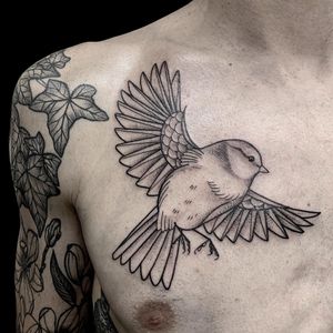 Elegant black and gray bird motif chest tattoo in London, GB. Perfect for a timeless and sophisticated look.