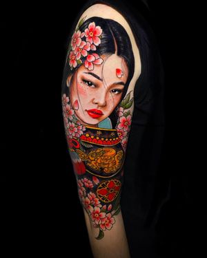 Capture the elegance of a geisha and the beauty of cherry blossoms with this stunning upper arm tattoo. Located in London, GB.