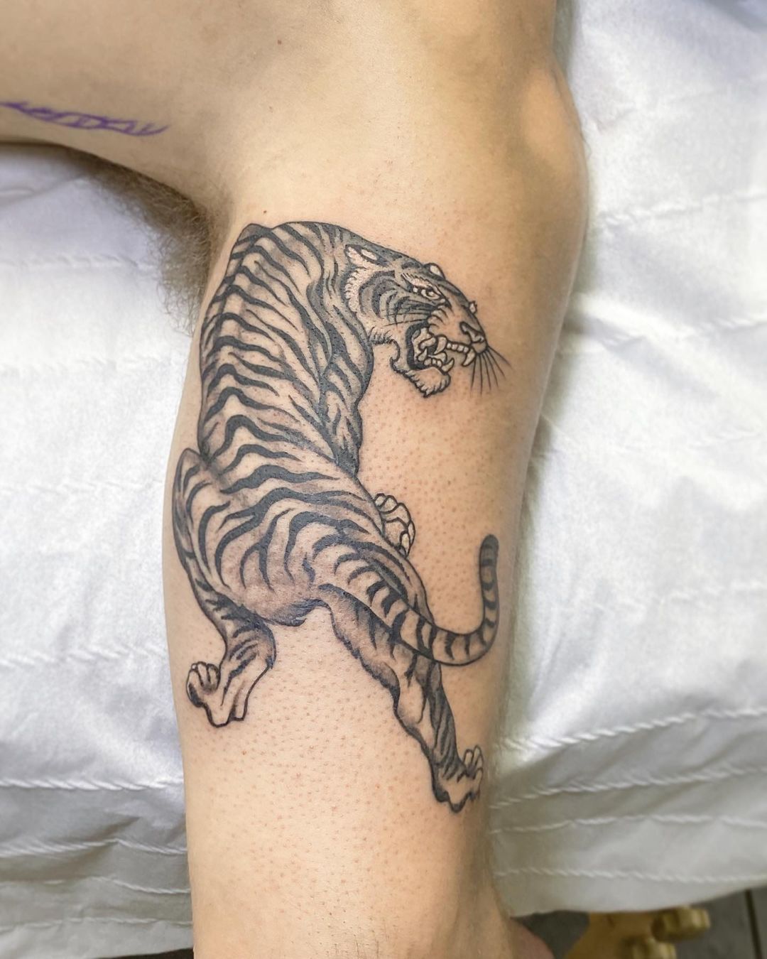 Fine line tiger tattoo on the right upper arm.