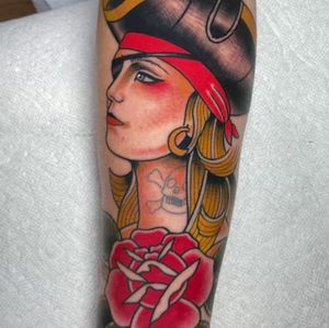 Illustrative traditional tattoo featuring a woman pirate with skull, flower, earrings, and hat. Located in Los Angeles.