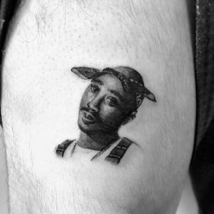 Get a bold blackwork tattoo of Tupac on your upper arm in Los Angeles for a striking and unique piece of art.