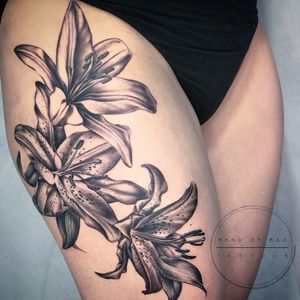 Experience the beauty of a detailed lilly tattoo by Raa, blending realism and illustrative blackwork style.