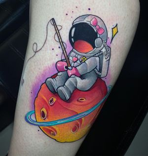 Explore the cosmos with this colorful new school tattoo featuring a moon, star, astronaut, and fishing rod on the upper arm.