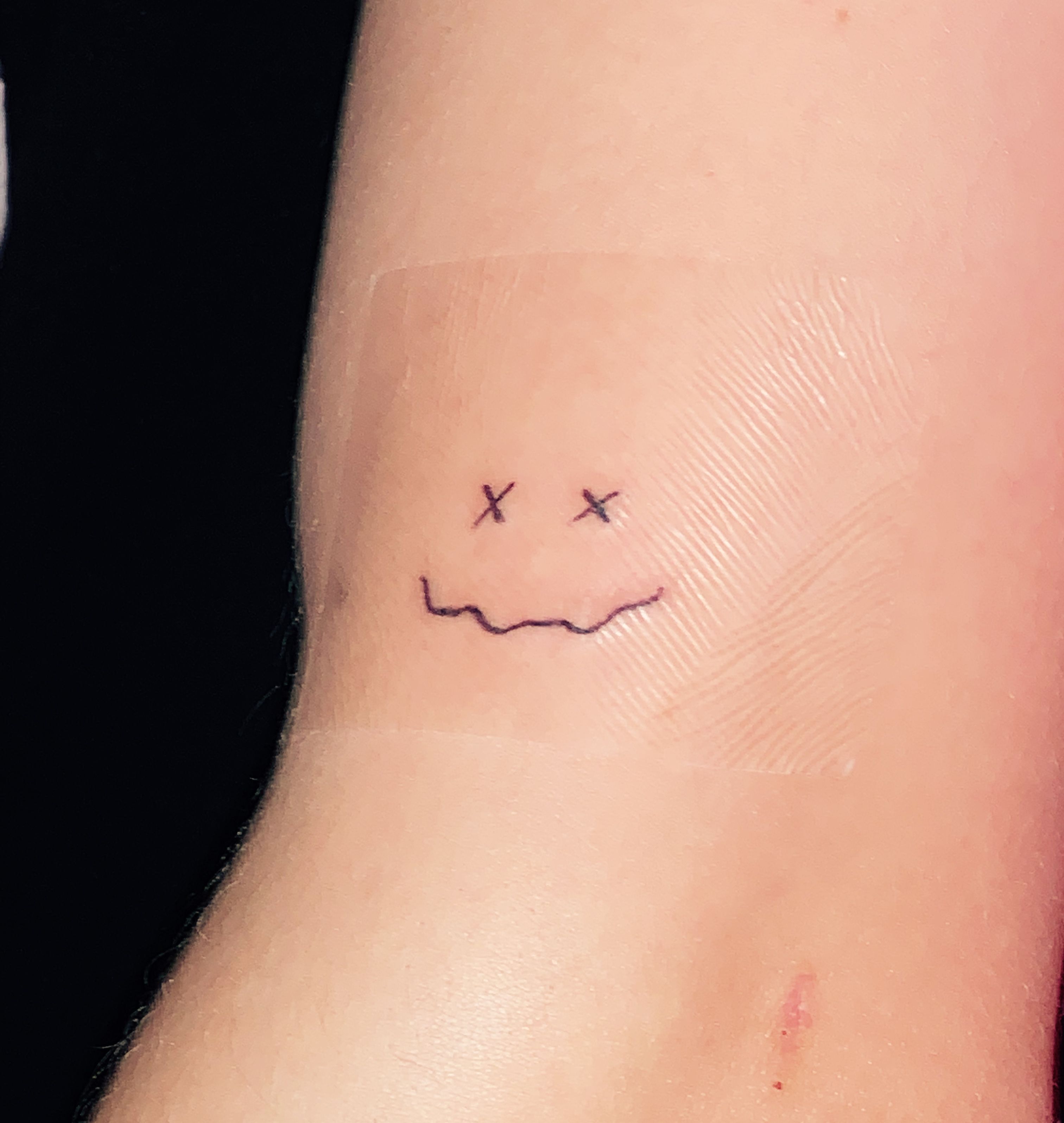 Smiley face tattoo placed on the hand