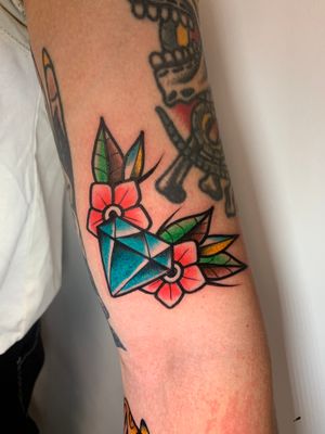 Get a stunning illustrative traditional tattoo featuring a vibrant flower and diamond design on your forearm in London, GB.