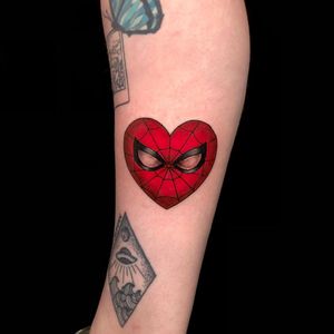 Get a colorful new school tattoo on your forearm featuring Spiderman and a heart motif by Sandro Secchin.