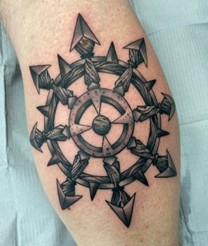 Discover the intricate blackwork design of a steering wheel on the lower leg by renowned artist Darren Brass.