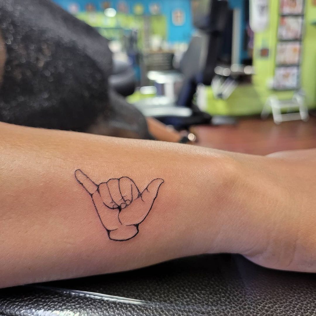 Hand poked shaka sign tattoo on the thigh