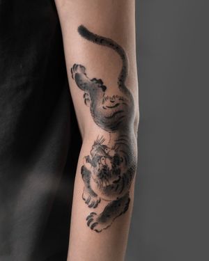 Impressive blackwork design of a fierce tiger by FKM TATTOO, perfect for arm placement.