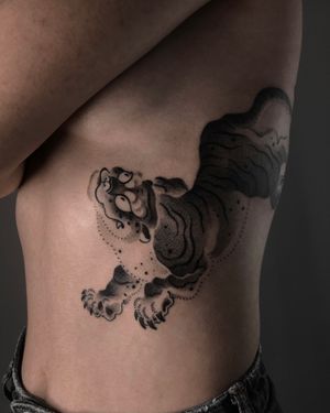 Elegant black and gray tiger design on ribs by FKM TATTOO, blending blackwork and dotwork styles.