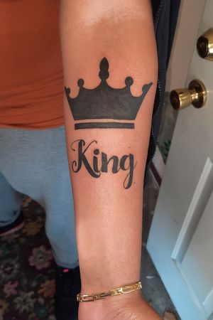 Crown tattoo in all black with littering. 