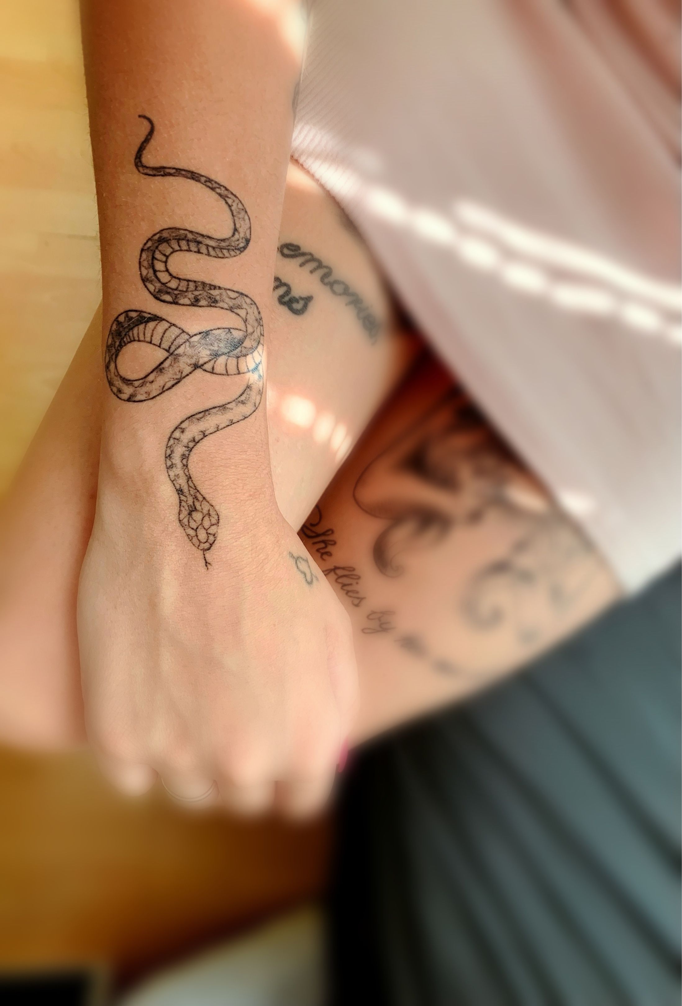 Fine line snake bracelet tattoo in red ink.