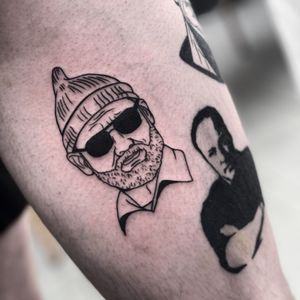 Blackwork tattoo of a man with beard, glasses, and hat on arm by Miss Vampira