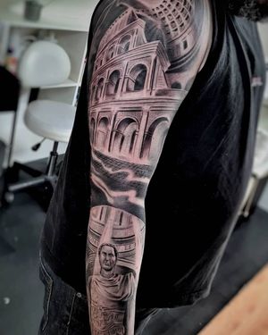 Intricate design by Mauro Imperatori featuring a stunning black and gray coliseum and architectural elements on a sleeve tattoo