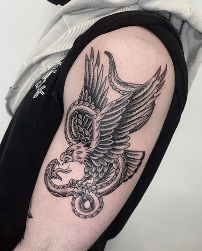 Get a bold blackwork snake and eagle tattoo on your upper arm in Los Angeles for a fierce and unique addition to your body art. Expertly crafted in an illustrative style.