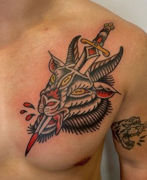 Get a bold and classic illustrative tattoo featuring a powerful goat, sharp dagger, and splashes of blood on your chest in Los Angeles.